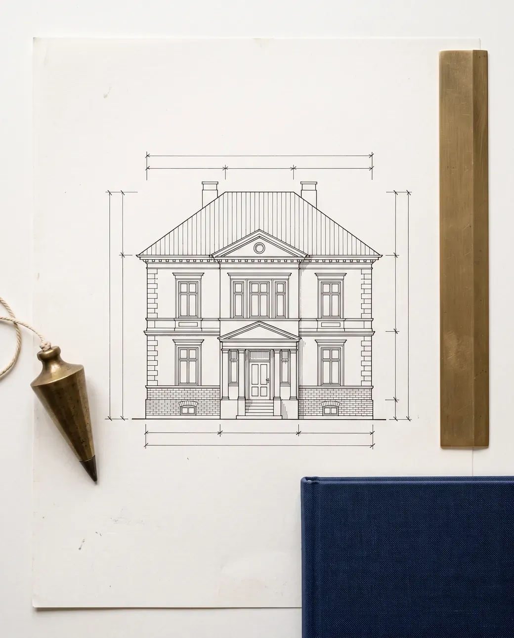 Ansicht einer Stadtvilla als Zeichnung mit Maßketten, daneben Lot, Messinglineal und Mappe